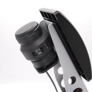 May include: A black camera lens with a silver mount attached to a black stand. The lens has a black cap on the front and a silver ring around the middle.