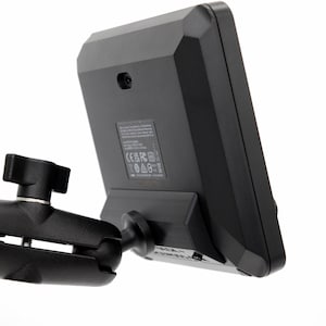 Może przedstawiać: Czarny, elektroniczny wyświetlacz z prostokątnym ekranem zamontowany na czarnym, regulowanym ramieniu. Urządzenie jest ustawione pod kątem, odsłaniając tylny panel z etykietami i małym aparatem. Ramię ma przegub kulowy dla elastycznego pozycjonowania.