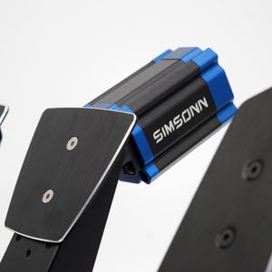 Könnte beinhalten: Nahaufnahme eines schwarzen und blauen SIMSONN-Geräts. Das Gerät ist auf einer schwarzen Metallstruktur mit silbernen Akzenten montiert. Das SIMSONN-Logo ist weiß. Der Hintergrund ist weiß.