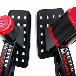 Peut inclure: Deux composants mécaniques noirs et rouges avec le texte "ASETEK" en rouge. Chaque composant a un dessus rouge et un corps noir. Les composants sont montés sur des plaques noires avec plusieurs trous.