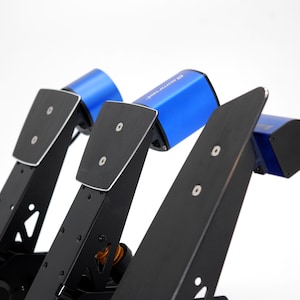 May include: Close-up of a set of black racing pedals with blue accents. The pedals have a sleek, modern design with a matte finish. The image is well-lit, highlighting the details of the product.