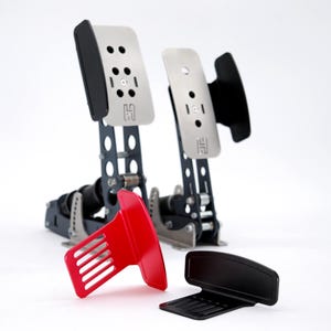 Puede incluir: Juego de pedales de simulador de carreras con componentes plateados, negros y rojos. Los pedales tienen una base de metal con múltiples agujeros y una placa para el pie plateada. Un componente rojo y otro negro están separados.