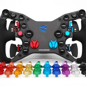 May include: A racing wheel in black and grey with a carbon fibre centre and black grips. It features multiple coloured buttons and levers. A selection of coloured knobs are displayed below the wheel.