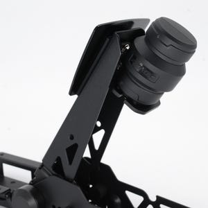 May include: A black metal device with a cylindrical component and angled supports. The cylindrical part has a textured surface and the word "SAGE" is visible. The device is set against a white background.