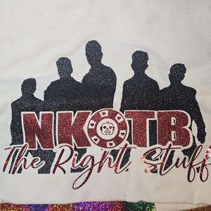 May include: White t-shirt featuring a glittery design with the text "NKOTB The Right Stuff". The design includes silhouettes of five figures and a poker chip graphic. The text is in red glitter.