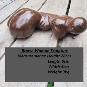 May include: Brown woman sculpture made of stone. Measurements: Height 28 inches, Length 8 inches, Width 5 inches, Weight 3 kg.