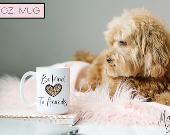 Könnte beinhalten: Weiße Keramiktasse mit 440 ml Fassungsvermögen, einem schwarzen Herzen mit Leopardenmuster und dem Text "Be Kind To Animals".