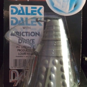 May include: A grey Dalek toy with a friction drive. The toy is packaged in a clear plastic blister pack with a blue and white Doctor Who logo. The packaging also features a blue and white TARDIS.