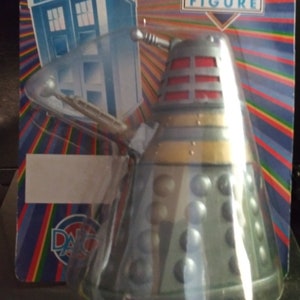 May include: A Doctor Who figure of a Dalek, a silver and grey robot with a red dome and a black and gold base. The figure is packaged on a colourful card with the words "Doctor Who Figure" and "One of a series with moveable limbs".