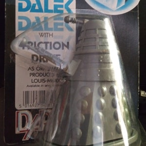 May include: A grey plastic toy Dalek from the Doctor Who television series. The Dalek has a black dome with a silver top and a black gun. The packaging says "Doctor Who Dalek with Friction Drive" and "As originally produced by Louis Marx".