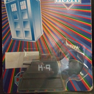 May include: A Doctor Who action figure with a blue police box and the text "Doctor Who Figure" and "H.Q." on the packaging.