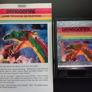 May include: A vintage Atari video game cartridge for Dragonfire. The cartridge is black with a silver label featuring a colorful dragon illustration and the game title. The text "for Use with Atari & Sears Video Systems" is printed on the label.