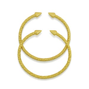 May include: Two gold-colored, open-ended bangles with a textured, woven pattern. Each bangle has a pointed, triangular tip at each end. The bangles are displayed on a white background.