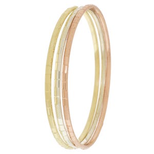 Puede incluir: Tres pulseras de metal en oro, plata y oro rosa. Cada pulsera tiene un patrón rectangular texturizado. Las pulseras están apiladas, creando un aspecto en capas. El fondo es blanco liso.