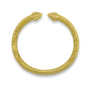 May include: A gold-colored open cuff bracelet. The bracelet has a detailed floral and geometric pattern along the band. The ends of the bracelet are shaped like stylized snake heads.