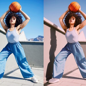 May include: A person in a light blue tank top and wide-leg blue pants holds an orange basketball overhead. The person is standing outside on a sunny day, with a clear blue sky in the background. White sneakers complete the outfit.