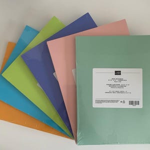 May include: A fan-shaped stack of rectangular cardstock sheets in assorted colors including orange, blue, lime green, purple, pink, and mint green. Each pack is wrapped in clear plastic, with the top mint green pack featuring a white label.
