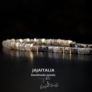 K&ouml;nnte beinhalten: Ein Perlenarmband mit quadratischen, grauen und schwarzen Steinen und goldfarbenen Akzenten. Das handgefertigte Armband tr&auml;gt den Text "JAJAITALIA Handmade Jewels by Giulia Torelli" im Bild.