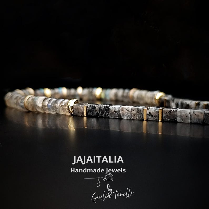 K&ouml;nnte beinhalten: Ein Perlenarmband mit quadratischen, grauen und schwarzen Steinen und goldfarbenen Akzenten. Das handgefertigte Armband tr&auml;gt den Text "JAJAITALIA Handmade Jewels by Giulia Torelli" im Bild.