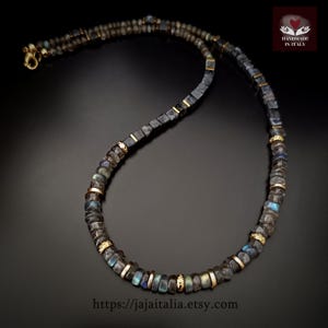 K&ouml;nnte beinhalten: Eine handgefertigte Halskette mit dunkelgrauen Labradoritperlen mit goldfarbenen Akzenten. Die Halskette hat einen Karabinerverschluss und wird auf schwarzem Hintergrund pr&auml;sentiert. Die Etsy-Shop-URL ist unten sichtbar.