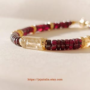 Könnte beinhalten: Ein Armband mit abwechselnden Abschnitten aus tiefroten und goldgelben Edelsteinen. Das Armband enthält einen großen, rechteckigen, hellfarbigen Kristall und goldfarbene Metallakzente. Die Etsy-Shop-URL ist unten im Bild sichtbar.