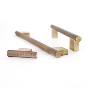 Pode incluir: Três puxadores de armário de latão com um padrão texturizado em forma de diamante. Os puxadores são de tamanhos diferentes, sendo o maior um puxador de 30,5 cm.