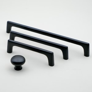 May include: Four black cabinet pulls in different sizes, including a small knob. The pulls are all made of metal and have a sleek, modern design.