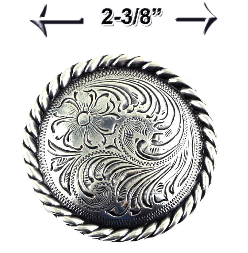 May include: Silver belt buckle with a rope design border and a floral engraved design. The buckle measures 2-3/8 inches in diameter.