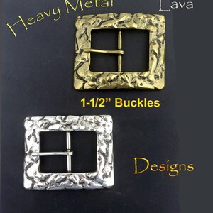 May include: Two square metal buckles with textured, lava-like designs. One is gold-toned, the other silver. The text "Heavy Metal Lava" and "1-1/2" Buckles" are visible. The word "Designs" is also present.