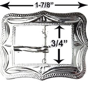 May include: Silver-colored rectangular belt buckle with an ornate, embossed design. The buckle measures 1-7/8 inches wide and 1-1/2 inches tall, with a 3/4-inch opening for the belt strap. The edges are scalloped and dotted.