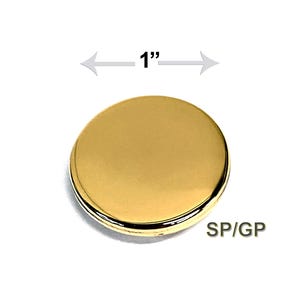 May include: A gold-colored, round object with a diameter of 1 inch. The object has a shiny, metallic finish and a thin, black border. The text "SP/GP" is visible on the object.