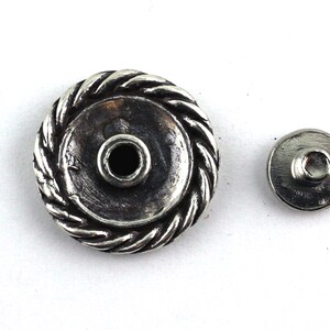 May include: Silver-toned metal button with a rope-like design around the edge. The button has a small hole in the center and comes with a matching back piece.