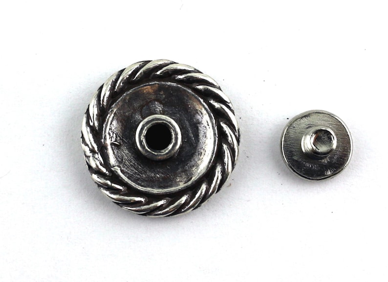 May include: Silver-toned metal button with a rope-like design around the edge. The button has a small hole in the center and comes with a matching back piece.