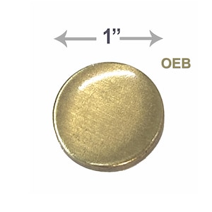 May include: A single, round, brass-colored button, approximately 1 inch in diameter. The button has a slightly domed surface and a shiny finish. The letters "OEB" are visible in the upper right corner.