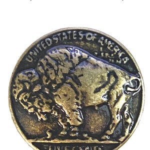 May include: A gold-colored metal replica of a US five-cent coin featuring a buffalo, with the words "UNITED STATES OF AMERICA" and "FIVE CENTS" inscribed around the edge. The coin is 7/8 inches in diameter.