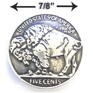 May include: A silver-colored Buffalo nickel coin with the inscription "UNITED STATES OF AMERICA" and "FIVE CENTS" on the back. The coin is 7/8 inches in diameter.