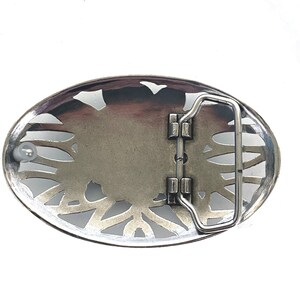 May include: Silver-toned belt buckle with an intricate, floral design. The buckle has a hinged closure and a smooth, polished finish.