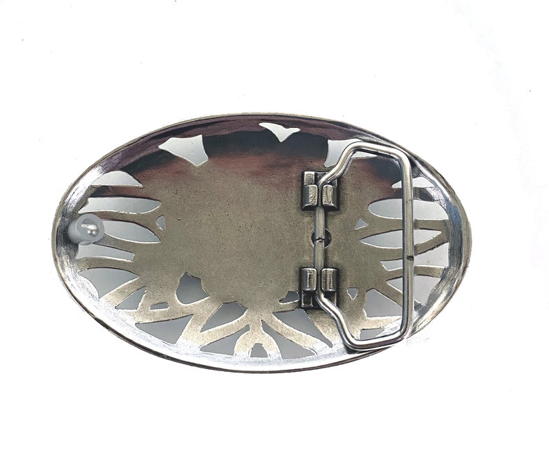 May include: Silver-toned belt buckle with an intricate, floral design. The buckle has a hinged closure and a smooth, polished finish.