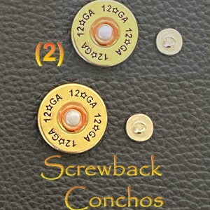 May include: Two gold-colored metal conchos with a screwback design. Each concho features a round, raised center with a white pearl-like button and the text "12☆GA 12☆GA" around the edge.