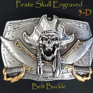 May include: A silver belt buckle with a 3-D engraved pirate skull wearing a hat and holding crossed swords. The buckle has a textured surface and gold accents.