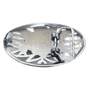 May include: Silver-toned metal belt buckle with an oval shape and a floral design. The buckle has a metal loop for attaching a belt.