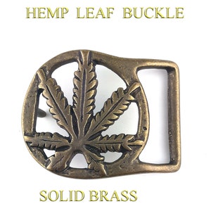 May include: A solid brass belt buckle featuring a detailed hemp leaf design.  The buckle is a classic, simple design with a rectangular shape and a rounded, leaf-shaped front.
