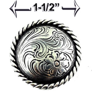 May include: Silver-toned metal belt buckle with a rope-like border and a floral design. The buckle measures 1-1/2 inches in diameter.