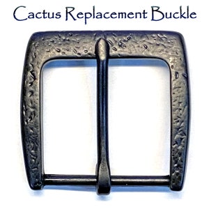 May include: Black metal belt buckle with an engraved cactus design. The buckle is textured and has a vintage look.
