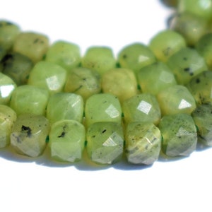 Könnte beinhalten: Eine Kette aus grünen Jadeperlen mit facettierter quadratischer Form. Die Perlen sind auf einem durchsichtigen Faden aufgefädelt und in einem Kreis angeordnet.