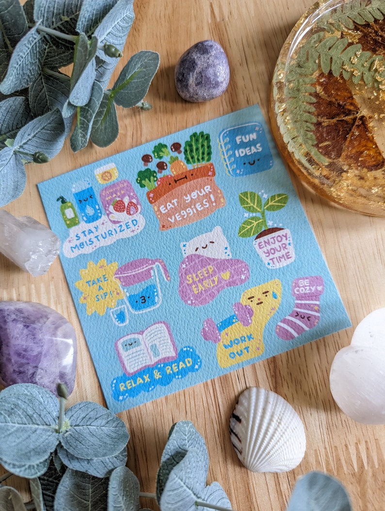 May include: A blue card with colorful illustrations and text. The text includes "Stay moisturized", "Eat your veggies", "Sleep early", "Enjoy your time", "Take a sip", "Relax & read", "Work out", and "Be cozy".