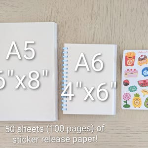 May include: Two white spiral-bound notebooks, A5 size (15.24cm x 20.32cm) and A6 size (10.16cm x 15.24cm), and a sheet of colorful stickers. The notebooks have pink and blue spirals. The text reads "50 sheets (100 pages) of sticker release paper!"