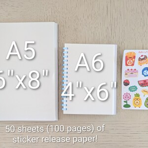 May include: Two white spiral-bound notebooks, A5 size (6" x 8") and A6 size (4" x 6"), and a sheet of colorful stickers. The notebooks have pink and blue spirals. The text reads "50 sheets (100 pages) of sticker release paper!"