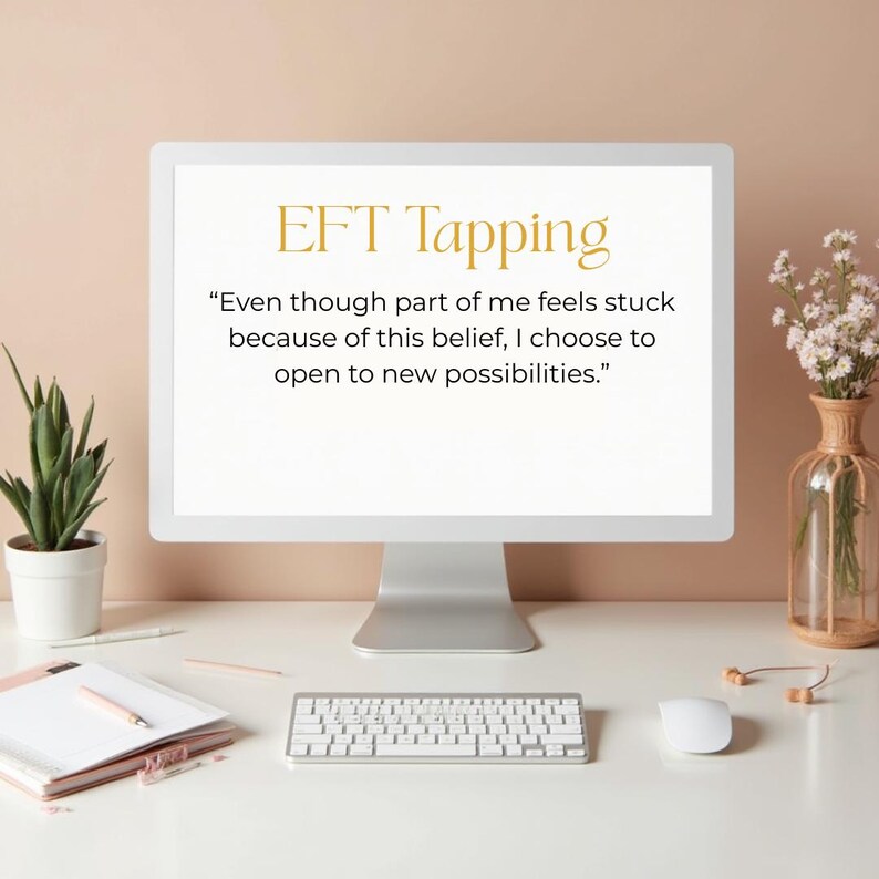 Może przedstawiać: Monitor komputera wyświetla tekst "EFT Tapping" i inspirujący cytat. Na biurku znajdują się biała klawiatura, mysz i notatnik. Widoczna jest r&oacute;wnież mała roślina doniczkowa i wazon z kwiatami.