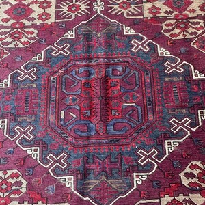 May include: A vintage rug with a traditional Persian design. The rug features a central medallion with intricate geometric patterns in shades of red, blue, and cream. The rug is woven with a high-quality wool and has a soft, luxurious feel.
